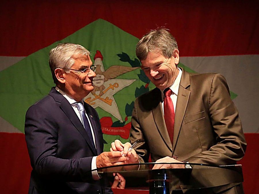 Assinatura de documento diante da bandeira de Santa Catarina